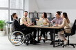© Pixel-Shot - Group of business people with man in wheelchair working at office