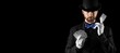 © Pixel-Shot - Male magician with cards showing tricks on dark background with space for text