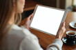 © Vadym - Woman holds blank tablet screen in cafe. Digital device with empty display on wooden table near coffee cup. Person uses portable gadget, online work at home or shop.