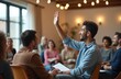 © Viktor - Young man raises hand during group discussion in a bright community hall. Diverse people listen attentively in a casual meeting setting. Event involves conversation and sharing ideas.