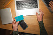 © Studio Marmellata - A person holds a debit card and a smartphone while using a laptop for online transactions.