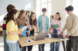 © Studio Romantic - Students and teacher lead classroom energy presentation. During lesson teenagers discuss a model wind turbine and a solar panel, planning projects. Clear concept of renewable energy education.