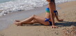 © camerist65 - Family with child sitting on sea shore looking at waves back view