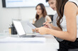 © BTM_Graphic - Close up of businesswoman reviewing documents and taking notes while working on laptop in modern office.