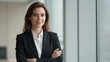 © FrameFlow - Confident female professional, dark business attire with blurred background, looking at viewer, window-lit office setting, commercial portraiture