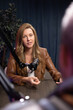 © fizkes - Woman host speaking into microphone during podcast recording session in studio. Guest sharing knowledge during digital interview, creating content for streaming media. Broadcasting, audio production