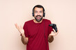 © luismolinero - Man playing with a video game controller over isolated wall with shocked facial expression