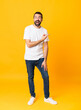 © luismolinero - Full-length shot of man with beard over isolated yellow background surprised and pointing side