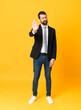 © luismolinero - Full-length shot of business man over isolated yellow background making stop gesture