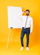 © luismolinero - Full-length shot of businessman giving a presentation on white board over isolated yellow background having doubts while scratching head