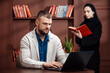 © wedmoments.stock - Corporate man typing on laptop while woman reads book in modern office. Business and teamwork concept.