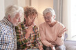 © luciano - Smiling Senior couple and Caregiver Sharing a Moment sitting together on sofa at home. Concept of assistance and help to our elderly