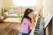 © AntonioDiaz - Young girl covering her face while learning piano, feeling frustrated with music lessons and practicing at home
