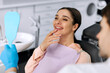 © Home-stock - Satisfied female patient sitting in dentist chair smiles after dental treatment while looking at her reflection in hand mirror