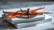 © arie - Precision drafting tools rest atop two white bound volumes against a textured background.