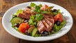 © LimeSky - Tuna salad with lettuce, cucumbers, tomatoes, olives, and avocados on a white plate at the table.