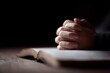 © Chandlerlikes - Hands clasped in prayer on open Bible spiritual devotion concept