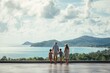 © SKIMP Art - family of four standing on the terrace overlooking the view vacation in phuket, thailand concept the asian family is wearing casual and holding hands while looking at the beach landscape Generative AI