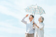 © buritora - An elderly couple, a married couple, a man and a woman using parasols under a blue sky (for protection against UV rays and heatstroke).
