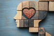 © lucky - wooden block silhouette of a human head with a heart-shaped brain piece at its center on a painted blue wood background suggesting compassion and mental wellbeing