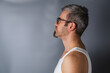 © mykhailo - Man in tank top poses against a gray background with side profile view