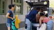 © DC Studio - Mother and family friends putting voyage baggage in car while getting ready for field trip departure. Multiethnic people loading luggage in vehicle trunk while unpatient little girl hurrying them