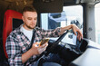 © Serhii - Truck driver using smartphone in vehicle