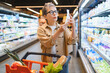© Serhii - Woman checking shopping list in grocery store aisle
