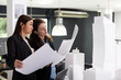 © DC Studio - Skilled architects study printed architectural blueprints, preparing for next construction site evaluation. Professional women crosschecking design variations for accurate project implementation.