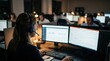© Justlight - Overtheshoulder view of a night shift claims assistant using dual monitors headset in place with a dimly lit team working in soft focus around.