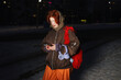 © Westend61 - Red haired woman with red bag outdoors on snowy winter evening