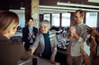 © Davor - Coworkers applaud as senior woman shakes hands in modern office