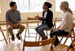 © Patrick - Three adults sharing and listening in a support group circle indoors, mental health counseling and peer discussion for communication and recovery