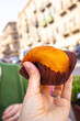 © Ina - Hand holding Sicilian arancini rice ball with filling on colorful street food table in Palermo, Sicily. Traditional Italian fried rice snack during local food exploration.