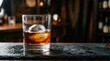 © tsinik - Premium whiskey glass with large round ice sphere on wet black slate. Dark moody bar background with blurred lights. Classic bourbon cocktail, luxury nightlife and evening relaxation concept.