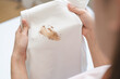 © KMPZZZ - Close up hand of housewife, maid woman holding white t-shirt, showing making cloth stain, spot dirty or smudge on clothes, dirt stains for cleaning before washing, making household working at home.