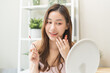 © KMPZZZ - Beauty cosmetic, cute asian young woman, girl make up face by applying lip gloss, pink or nude color on her mouth in the morning at home, look natural fashion style, skin care protection of people.