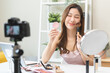 © KMPZZZ - Beauty blogger, asian young woman, girl vlogger makeup face, showing, reviews cosmetics products while recording video, tutorial to share on social media. Business online influencer on camera.