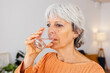 © Xavier Lorenzo - Senior adult woman in orange sweater drinking a glass of natural filtered water after wake up at home. Healthy lifestyle concept.