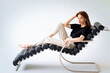 © sepy - Full length of a brunette haired woman relaxing in a modern chair against isolated background