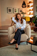 © sepy - Full length shot of an elegant middle-aged woman relaxing in an armchair in her stylish home