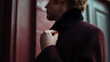 © A2Z AI  - Stylish man adjust coat collar against a warm toned background, partial view, showing elegant fashion and a contemplative mood outdoors