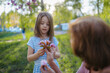 © Halfpoint - Grandmother and granddaughter holding spring blossoms together in sunny park.