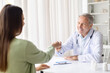 © Anastasiya - Senior male doctor greeting female patient with friendly fist bump during consultation. Medical professional building trust and positive relationship in healthcare environment