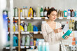 © JackF - Young woman buyer scanning qr code for shampoo or shower gel in household chemicals store