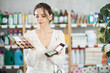 © JackF - Pleased young woman deciding which makeup items to buy in retail store