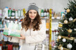 © JackF - Young female shopper buying gift set of care products in household chemicals store decorated for christmas