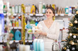 © JackF - Young woman buyer chooses chooses christmas gift set of cosmetics in decorated household chemicals store