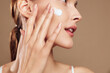 © SHOTPRIME STUDIO - Young woman applies moisturizing cream on her clean face with fingers closeup, skin care routine, natural makeup, beauty treatment, healthy glowing complexion