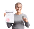 © Pixel-Shot - Mature woman with pills and calendar experiencing menopause on white background